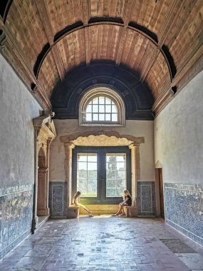 Tomar Portekiz - 08 09 2022: Büyük yatakhane koridorunun ana penceresinde iç manzara, Tomar Manastırı İsa, Tapınak Şövalyeleri mimarisi, pencere kenarında oturan iki kız