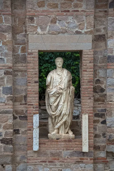 Merida / Spain - 05 12 2021: Statue of Roman man in ruins niche municipal forum of Augusta Emerita, Roman ruins of 1st-century structure with Corinthian columns and historic statues