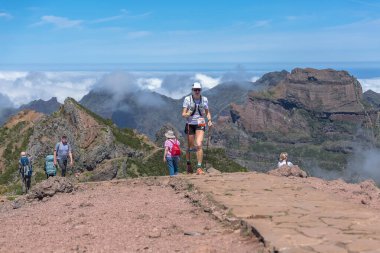 Madeira Adası Portekiz - 04 22 2023: Pico do Areeiro patika yarışını bitiren sıkı donanımlı atlet kadın, alçak bulutlar ve dağlar arka plan olarak, Madeira Adası, Portekiz