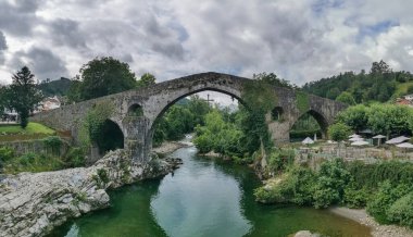 Leon Spain - 07 05 2021: Sella nehri üzerindeki Roma köprüsünde panoramik manzara, Cangas de Onis şehir merkezi, Picos de Europa veya Avrupa tepeleri, Cantabrian Dağları, İspanya