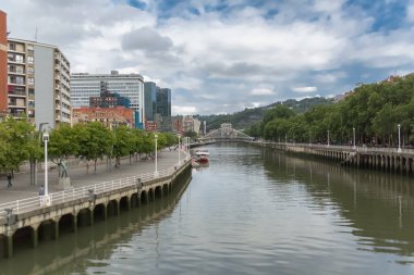 Bilbao İspanya - 07 05 2021: İkonik Zubizuri köprüsü ve Nervion nehri ve nehir kıyıları ile şehir merkezindeki Bilbao şehrinin dış görüntüsü