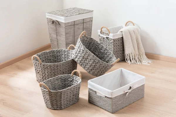 Empty gray wicker storage baskets set on wooden floor in a lighting interior room. Copy space