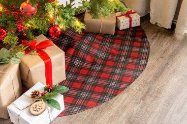 Noel ağacının altında hediyeler, ağaç bir eteğin üzerinde, ahşap bir zemine yerleştirilmiş. Büyük Noel kopyalama alanı