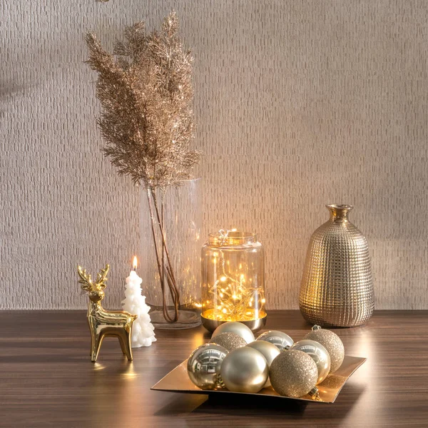 Christmas golden decorations, a pretty winter branch, and golden Christmas ball set on a wooden table in the interior
