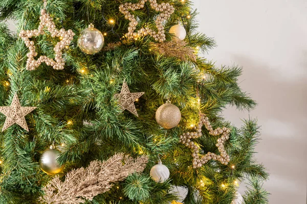 Altın ve gümüş süslemelerle süslenmiş Noel ağacı, Noel küreleri ve yıldızlar, yakın plan.