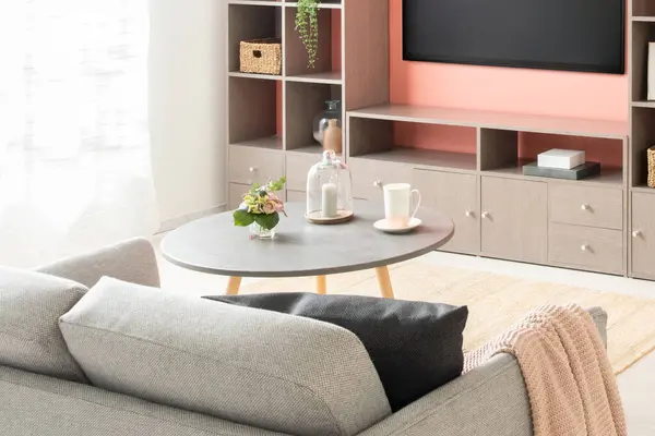 Contemporary Living Room Interior Featuring Grey Sofa, Coffee Table, Bookshelf, Nordic TV Cabinet Wall with Tea Table, Set on Wooden Flooring, Illuminated by Window Light.