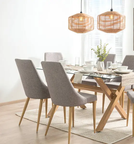 Glass-Top and Wood Base Rectangular Dining Table with Light Grey Fabric Dining Chairs, White Ceramic Dinnerware Set on a Table Runner in Modern Dining Room, Illuminated by Weave Rattan Pendant Lamps.