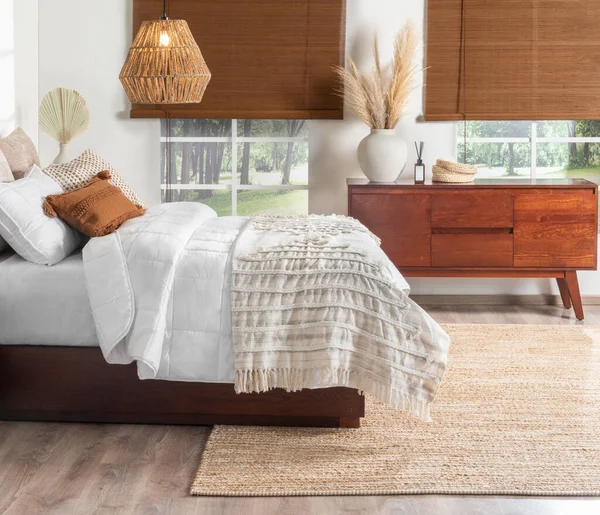 Welcoming Bedroom: King-Sized Bed Dressed in Soft White Quilts with Delicate Stitch Detailing, Accented by Cozy Textured Pillows in Earthy Tones, Rich Mahogany Bedside Wooden Cabinet, Area Rug.