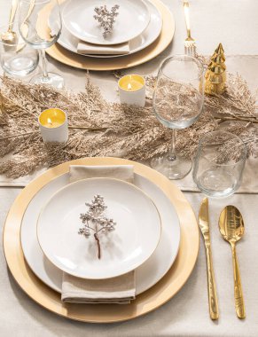 Festive Elegance Dining Table: Glimmering Gold-Rimmed Porcelain Plates on Golden Chargers, Paired with Gold Cutlery, Crystal Wine Glasses, and Ivory Candles amidst Gilded Foliage Decor, Top View. clipart