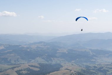 Mavi gökyüzünün ve Ukrayna 'daki bir dağ köyünün arka planına karşı bir paraglider. Yüksek kalite fotoğraf