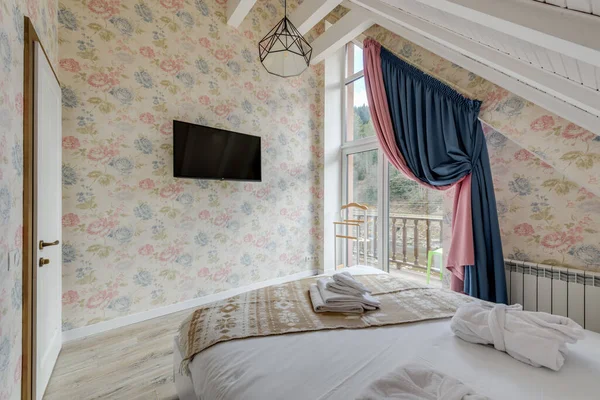 Large bright cozy room of the hotel room with a bed and a large window overlooking the forest. High quality photo