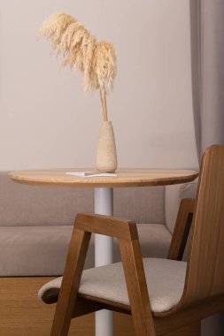 Kurumuş çiçekli sehpanın yanındaki ahşap tasarımcı sandalyesi. Yüksek kalite fotoğraf