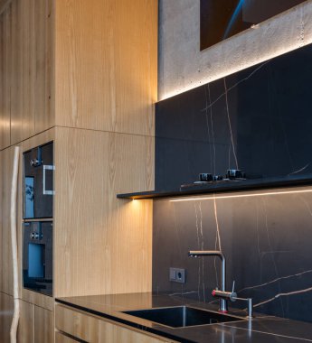 Dolap, ahşap tezgah ve yer döşemesi, armatürleri ve iç tasarımı mekanı geliştiren bir fırın içeren bir mutfak.