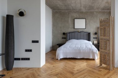 Konforlu bir yatak odası, ahşap döşeme ve doğal ışık için pencere donanımı olan bir ev.