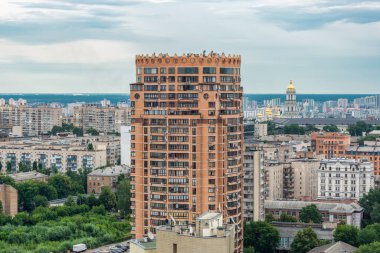 Arka planda tarihi mimarisi olan modern bir gökdelenli bina şehir manzarasının ortasında duruyor..