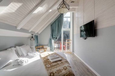 Parlak tavan arası yatak odası, modern dekor, doğal ışık, ve sakin kalmak için yatıştırıcı tarafsız tonlar.
