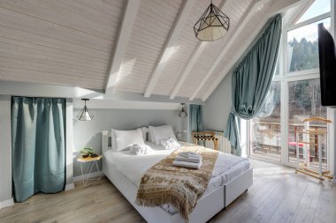 Modern dekor, doğal ışık ve geniş pencerelerden çarpıcı dağ manzaralı parlak tavan arası yatak odası..