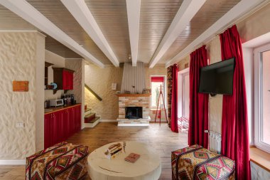 Oturma odası kırmızı bir dekor, şömine ve kırsal ve modern tasarım karışımı ile sıcak bir atmosfer yaratıyor.