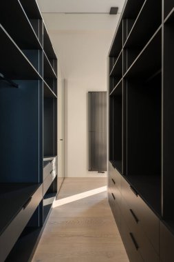 Modern bir dolap, şık ve ferah, parlak siyah raflar ve bol miktarda doğal ışık barındırıyor.