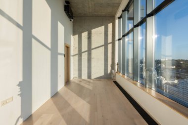 Geniş, modern bir oda. Geniş pencereli. Şehir manzarası sunuyor.