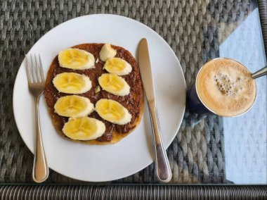Tabakta muzlu kek ve masada bir fincan kahve.
