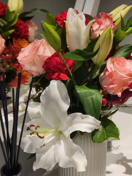 Flower arrangement with lilies and roses in a vase.
