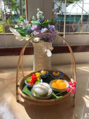 Çiçek vazosuyla birlikte sepetteki Tayland tatlısını.