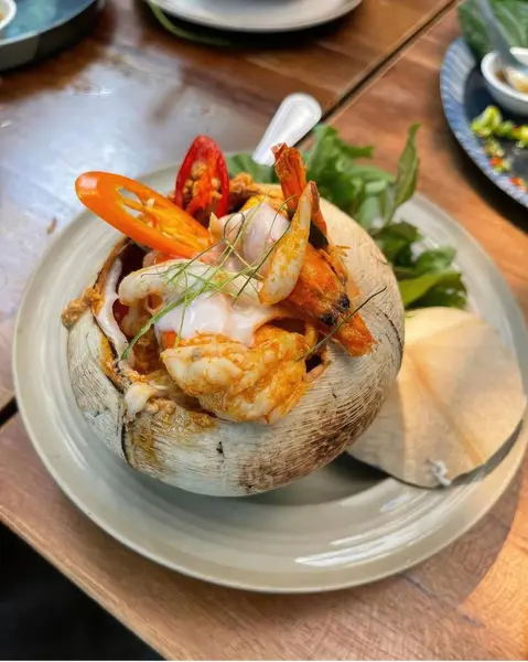 Ahşap masada Hindistan cevizi kabuğuyla baharatlı karides karıştır.