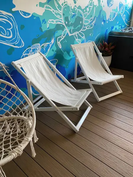 Wooden deck chairs on a deck with a blue wall in the background