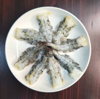 Tahta masada, beyaz tabakta kızarmış karides.