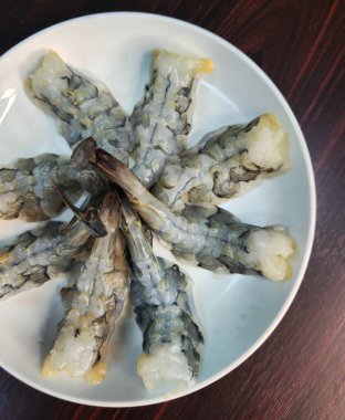 Tahta masadaki beyaz tabakta karides. Beyaz tabakta karides