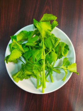 Kereviz yaprakları beyaz kâse içinde ahşap masa üzerinde, stok fotoğrafı