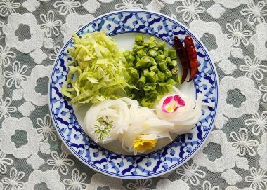 Şehriye yemekleri için mükemmel taze malzemeler içeren canlı bir tabak. Renkli bir mutfak deneyimi için lahana, bamya ve acılı pirinç eriştesi içeriyor..