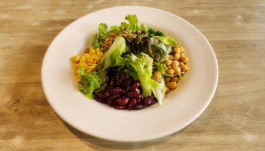 Marul, nohut ve fasulye içeren canlı bir sebze salatası. Sağlıklı bir yemek seçeneği için mükemmel. Taze malzemeler tat ve besin getirir..