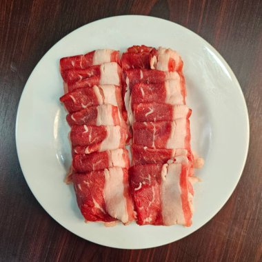 İnce dilimlenmiş taze et tabakta güzelce dizilmiş, sıcak tencere için mükemmel. Yemek hazırlamak için idealdir, bu kaliteli et her türlü mutfak deneyimine tat katar..