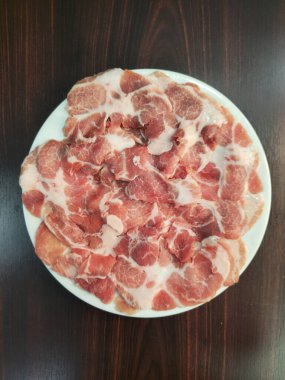 Beyaz bir tabakta sanatsal olarak düzenlenmiş taze kesilmiş domuz etinin canlı bir gösterisi. Mutfak projeleri ve gurme yemekleri için ideal. Yemek yapmayı seviyorsan gösteriş için mükemmelsin..