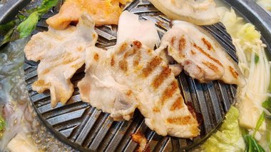 Canlı bir sahne, taze sebzeler ve lezzetli bir et suyuyla çevrili eşsiz bir ızgara tabakta ızgara et sergiliyor. Yemek meraklıları için mükemmel..