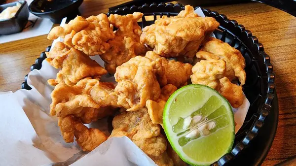 Taze limon dilimiyle servis edilen bu altın sarısı kızarmış tavuk ısırıklarının tadını çıkarın. Paylaşmak ya da atıştırmak için mükemmel bir aperatif..