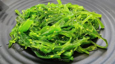 Bu canlı deniz yosunu salatası susam tohumlarıyla kaplı tazelik sergiliyor. Sağlık bilincine sahip restoranlar için ideal, parlak yeşil renkler ve besleyici malzemeler vurgulanıyor.