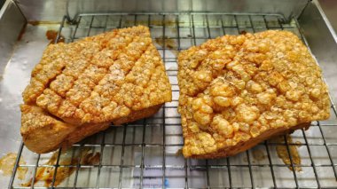 Bu görüntüde, metal bir rafta altın çıtırtılı domuz göbeği, gösterişli doku ve lezzet aşçılar ve yemek severler için mükemmel..