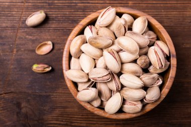 Top view, on an old wooden background, extreme close-up, a bowl with pistachios in shell.