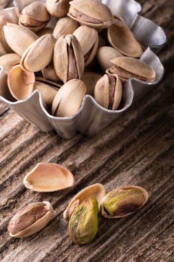 macro photo of some pistachios with and without shells on a rustic wooden background