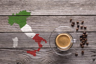 En üstteki cam bardakta espresso, kahve çekirdekleri ve gri desenli ahşap arka planda bayrağının renginde İtalya 'nın şekli..