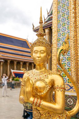Bir grup turist Wat Phra Kaew 'daki antik altın tapınağı veya Asya' nın en gözde turistik merkezlerinden biri olan Büyük Saray 'ı ziyaret ediyor. Bangkok, Tayland. Altın Kinnari heykeline odaklan..