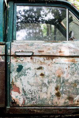 Eski zeytin yeşili bir arabanın yan görüntüsü, araba kapısının yüzeyinde boya soyulma, pürüzler ve aşınma. Antika araba..