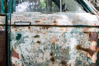 Eski zeytin yeşili bir arabanın yan görüntüsü, araba kapısının yüzeyinde boya soyulma, pürüzler ve aşınma. Antika araba..