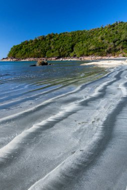 Güneşli bir yaz günündeki siyah kumsal manzarası sahildeki dalgalanmaları ve katmanları özetliyor. Koh Chang, Ranong, Thailan