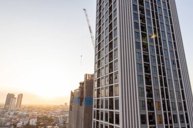 Gün batımında Bangkok ufuk çizgisinin havadan görünüşü, inşaat halindeki bina gökdelenin yanında..