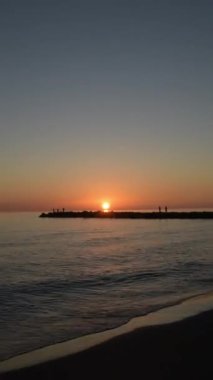 Sunset in the rock jetty of a beach. Time Lapse. 4K Vertical