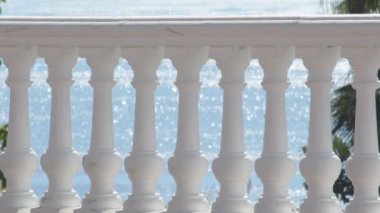 Güneşli bir günde, arkasında mavi deniz olan beyaz balustrad.